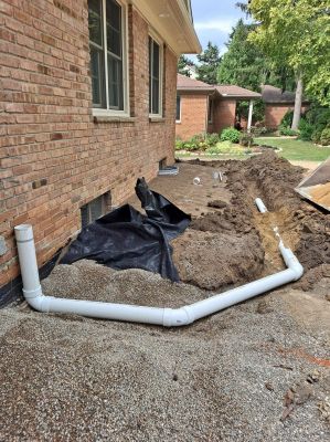 Downspout drains being installed to carry water away from the foundation.