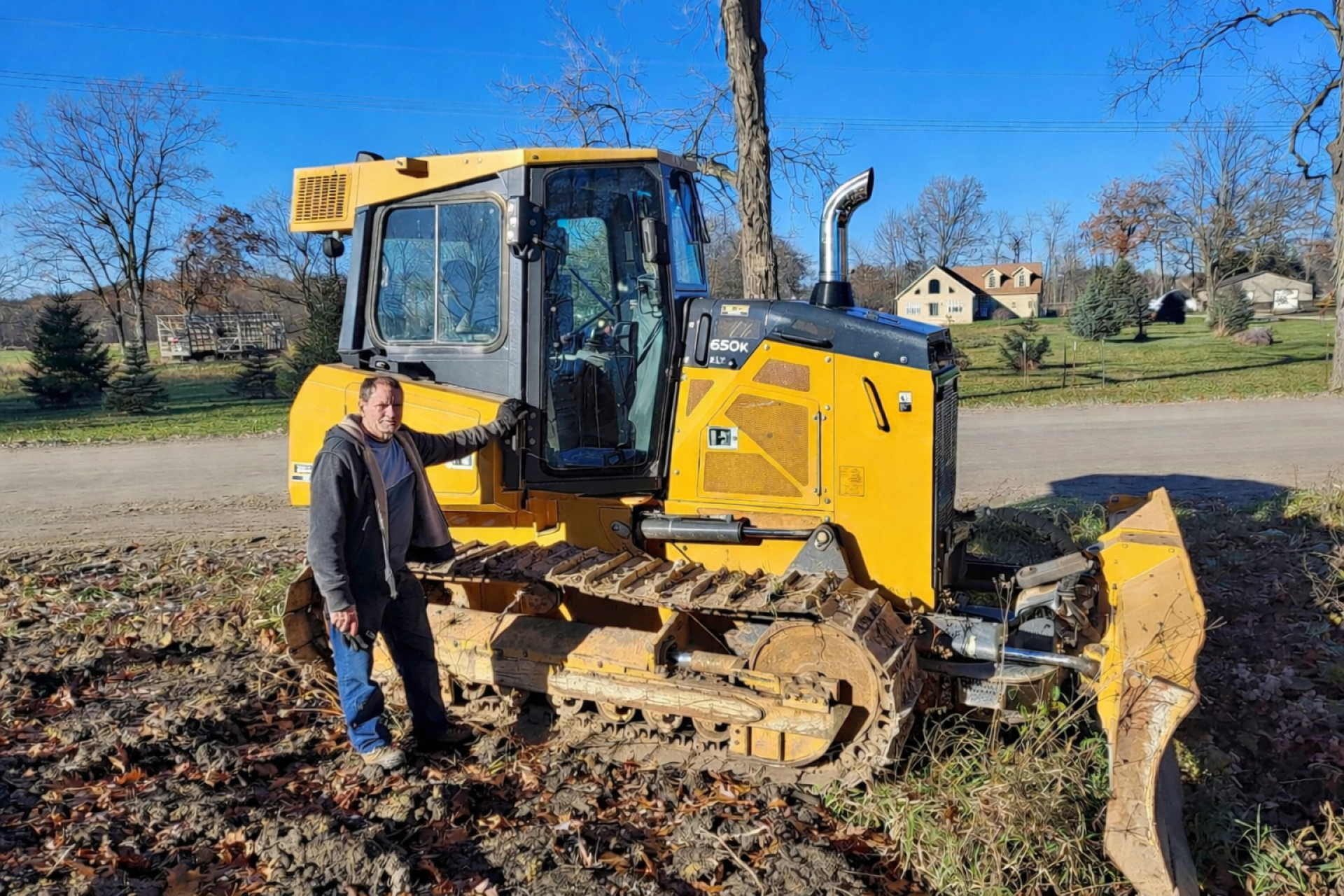 Excavation contractor from Always Building Company standing beside bulldozer on residential job site in Ann Arbor MI