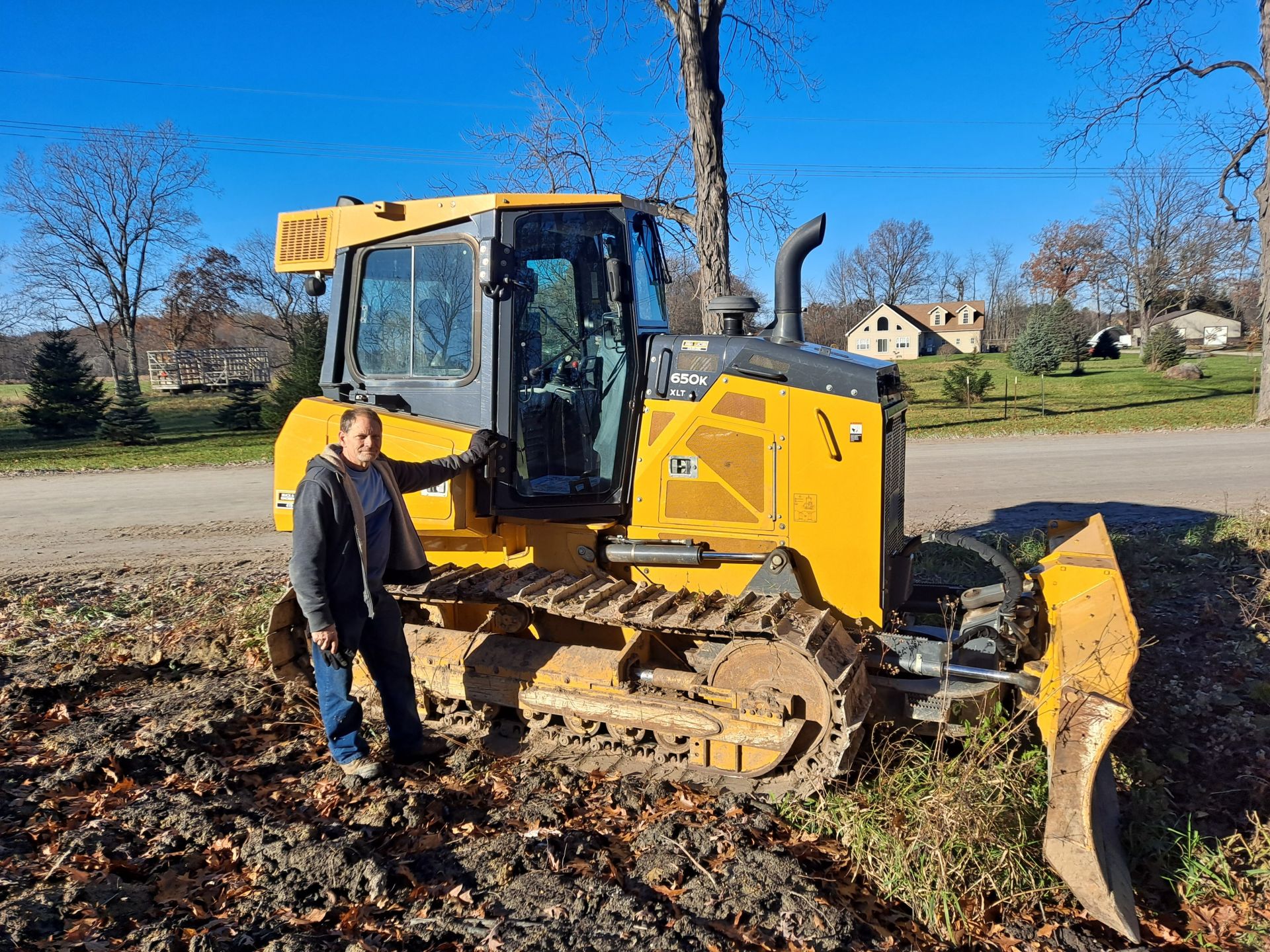 Excavation contractor from Always Building Company standing beside bulldozer on residential job site in Ann Arbor MI